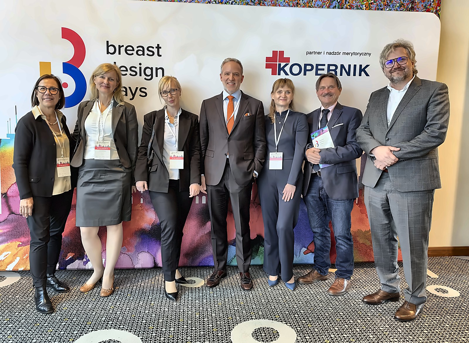 Dr. Nicholas Haddock with colleagues in front of the Breast Design Days backdrop in Łódź