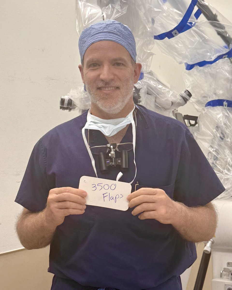 Dr. Nicholas Haddock in the operating room holding a 3,500 Flaps card